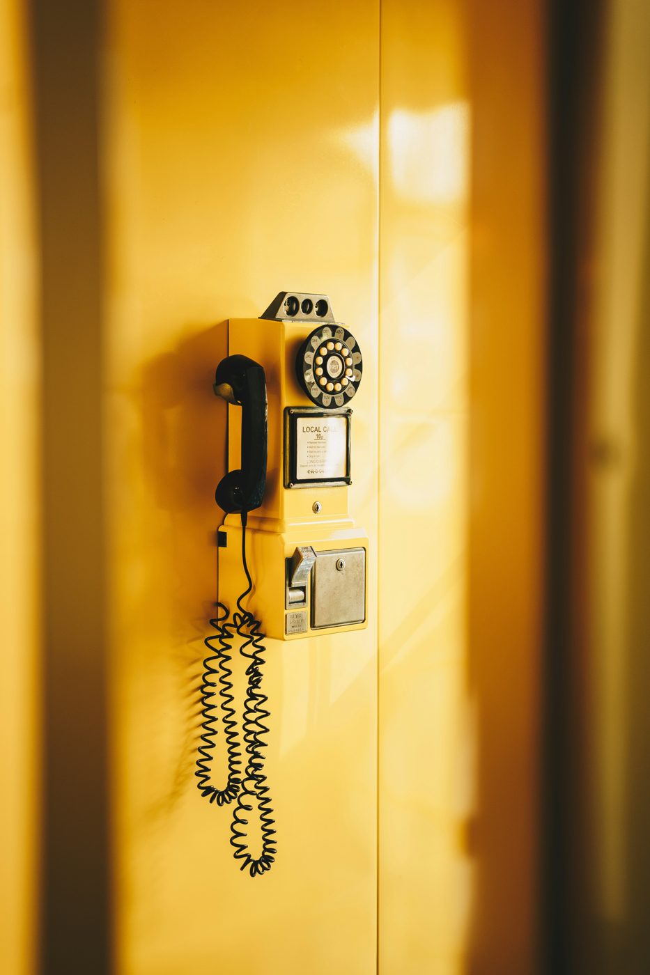 Gelbes Münztelefon an gelber Wand – eine Verbindung, die man selbst herstellt