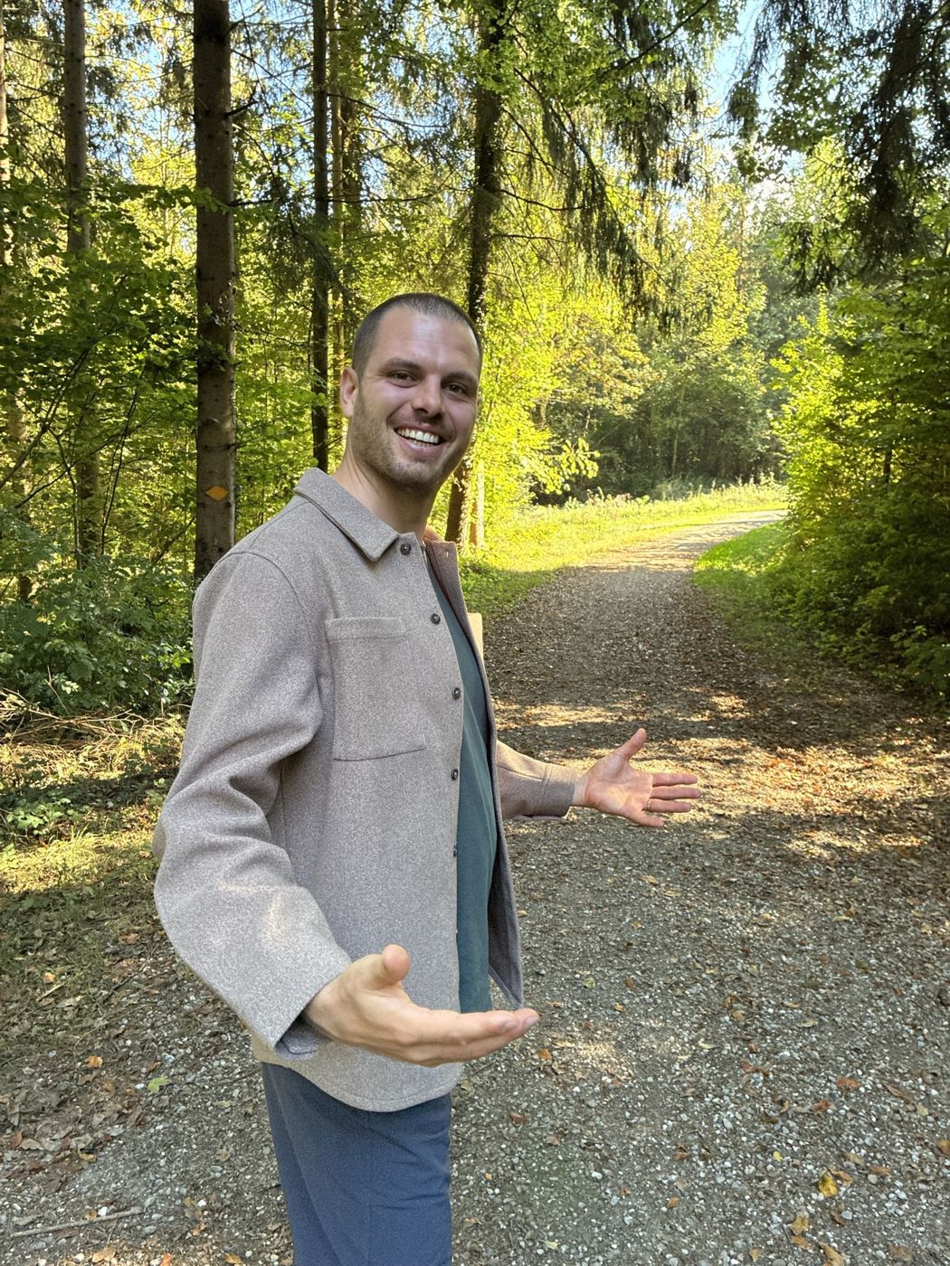 Valentin Lerchi lädt mit offenen Händen auf einen Waldweg ein – Wegbegleitung im Wald in der Region Winterthur